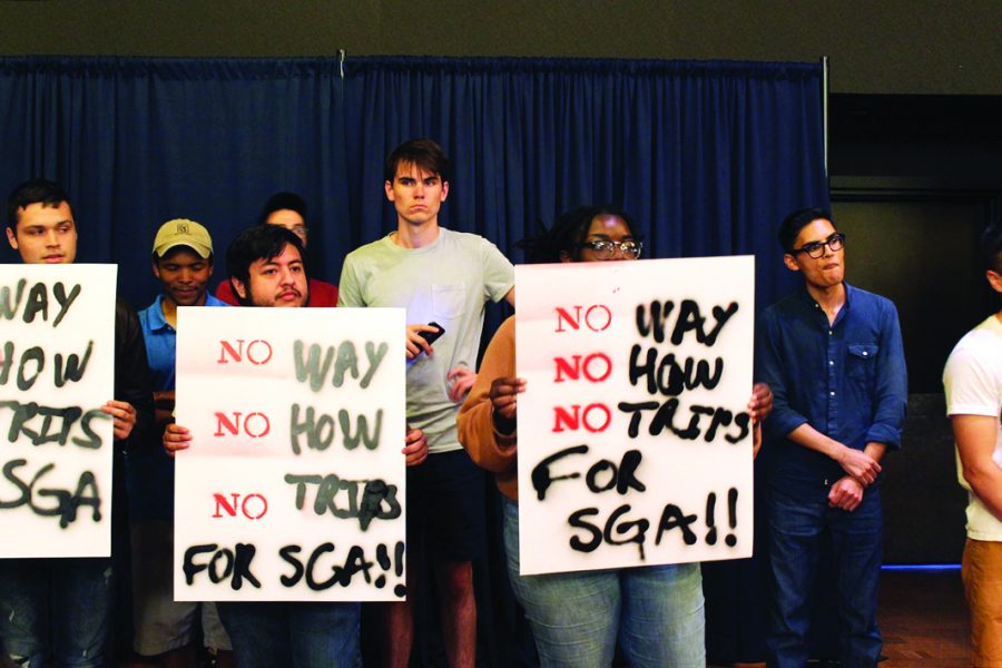 Students hold signs in protest to student government budget. Photo by Robyn Castro