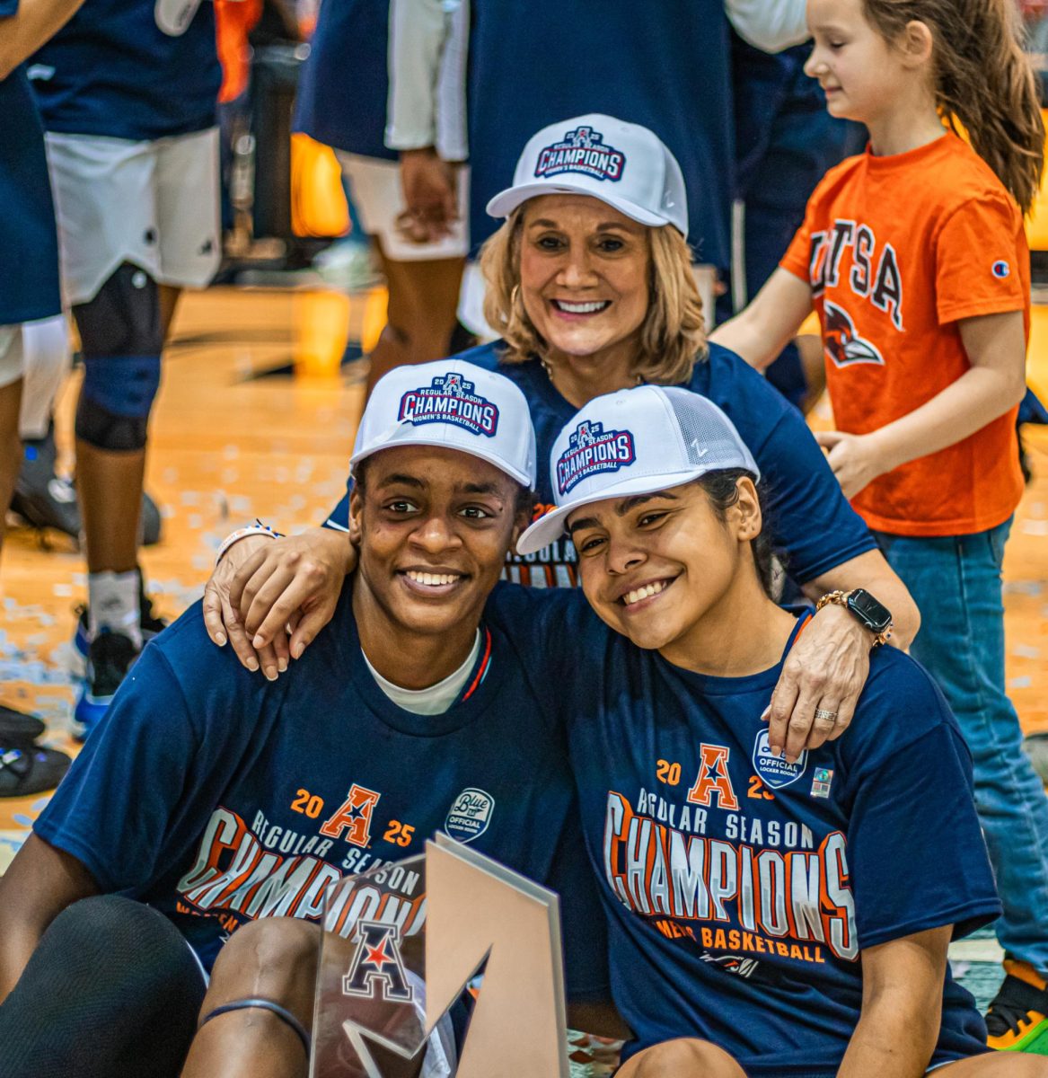 Jordyn Jenkins, Nina De Leon Negron and Karen Aston sit together on the court celebrating.